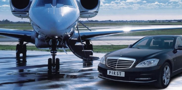 A front-view of a polished black luxury sedan from the SRB Limo fleet parked directly next to a private jet on an airport tarmac under a clear blue sky