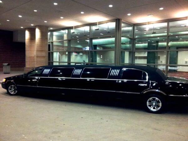 SRB Limo luxury black stretch limousine parked outside a professional corporate building entrance at dusk, representing reliable executive transportation services.