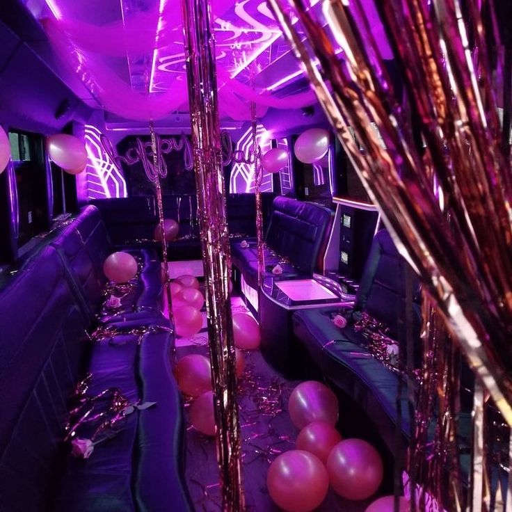Interior of an SRB Limo party bus featuring purple neon lighting, pink balloons, and gold streamers for a luxury event