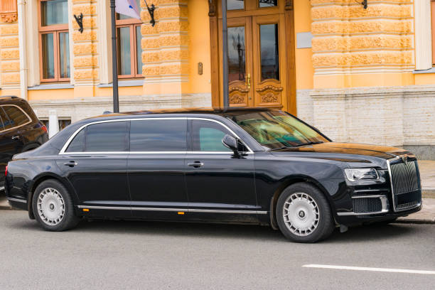 A side profile of a sleek, ultra-luxury black limousine from the SRB Limo fleet parked in front of a grand building with classic architectural details.