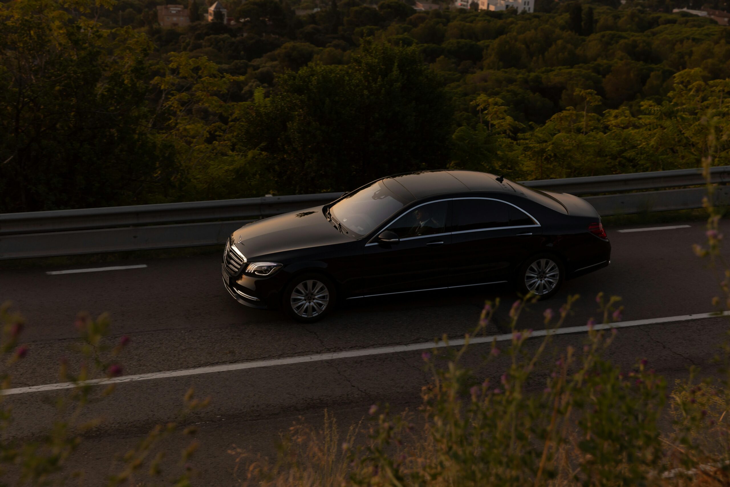 A black luxury sedan driving on a scenic road, representing our professional Fountain Hills Limo Service.