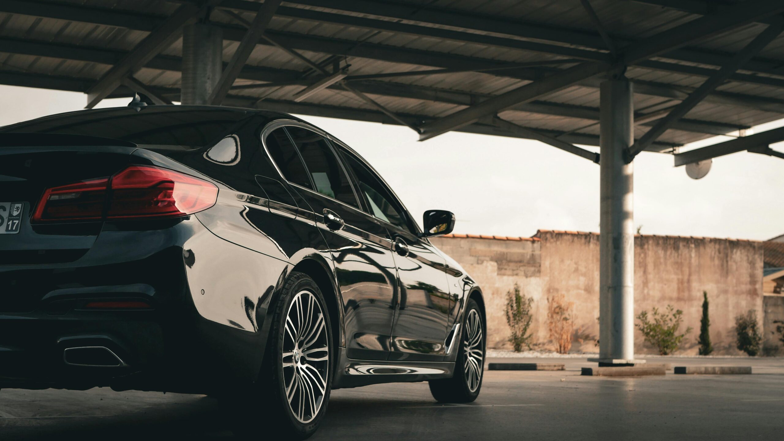 A rear view of a luxury black sedan parked in a shaded area, representing our premium Queen Creek limo service.